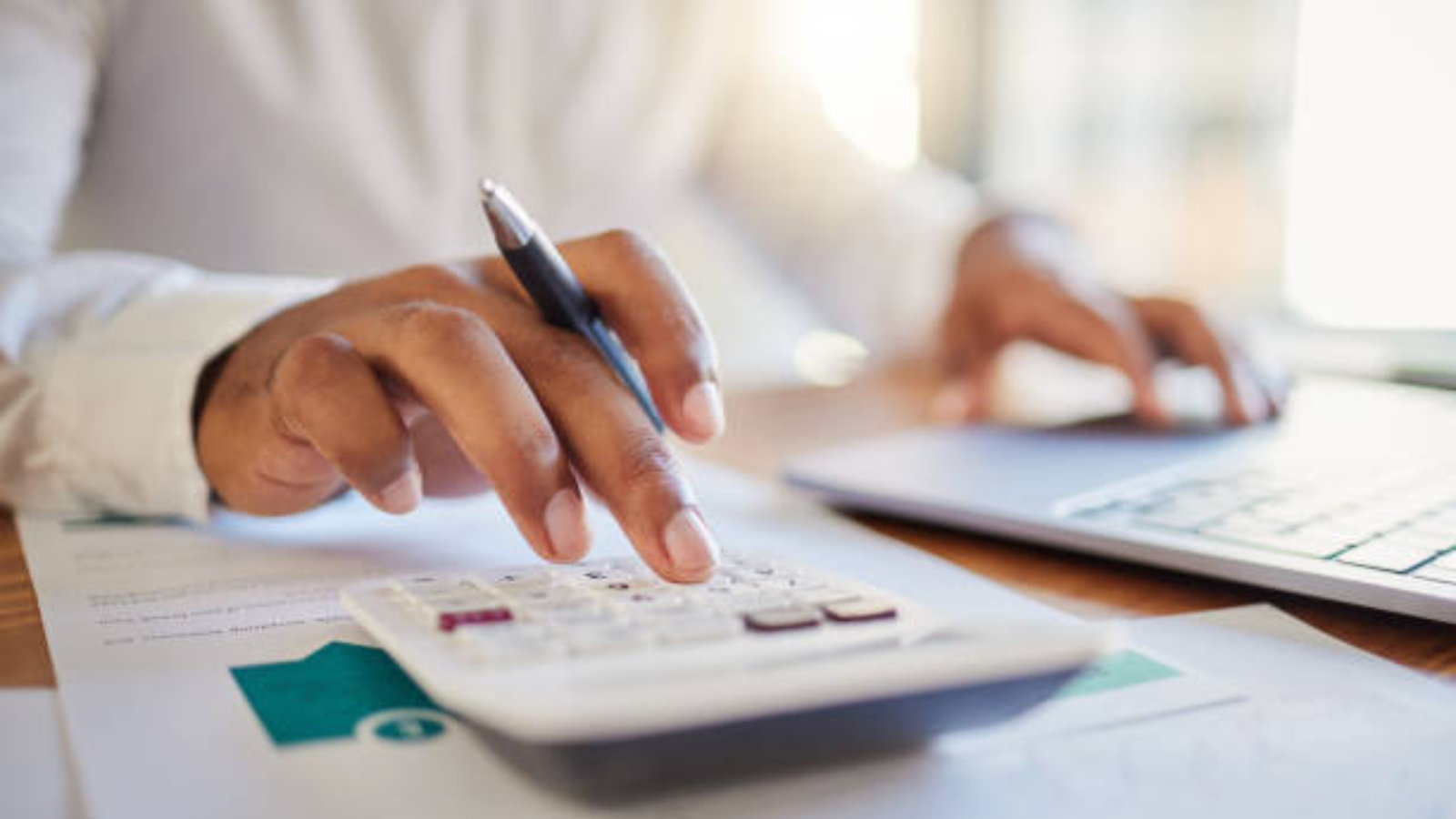 Finance, accounting and fintech, a man on a computer and calculator working out his business budget strategy. Businessman at his office desk, laptop, money management and financial investment online.